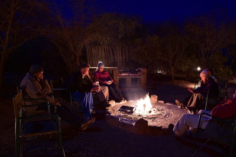 Guests gathered around a campfire in the bush at night