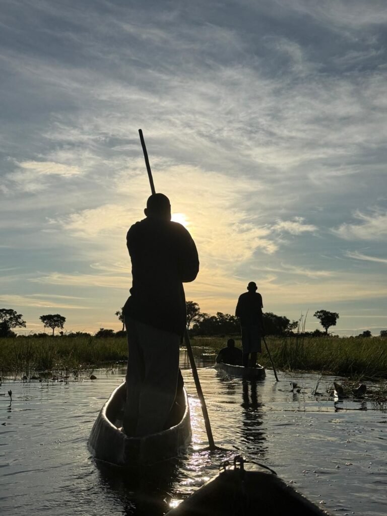 Mokoro poler silhouetted on the water in the Okavango Delta